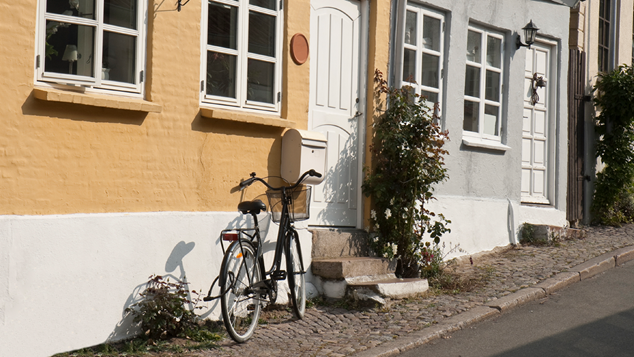 Cykel står på gaden foran hovedindgang til en bolig 