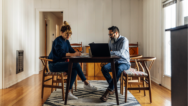 Par sidder ved bord med computer og papirer