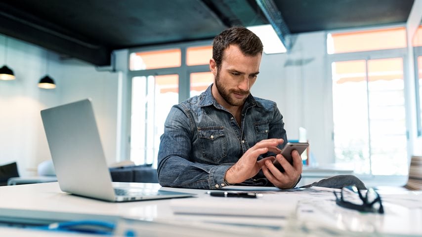 Mand bruger mobil ved sin arbejdsplads