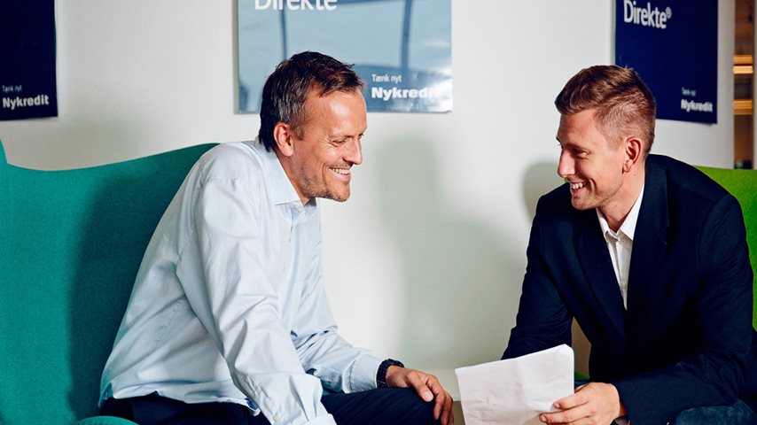 To mænd kigger på et papir og smiler