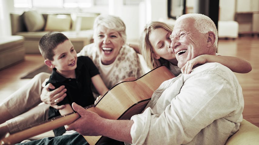Mand spiller guitar og griner med familien 