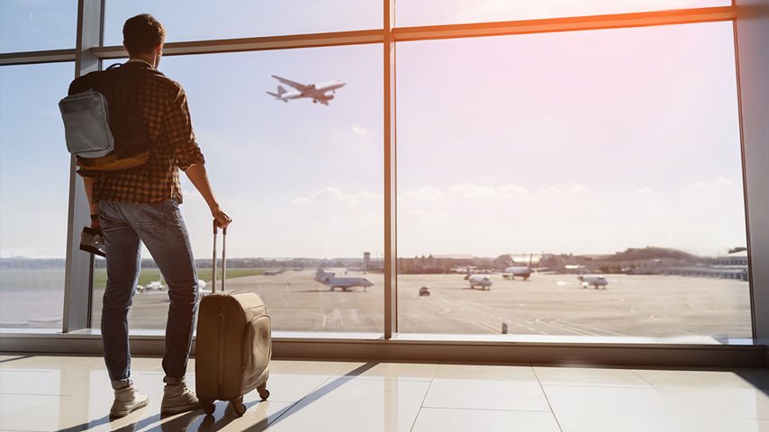 Mand med kuffert kigger på fly i lufthavnen